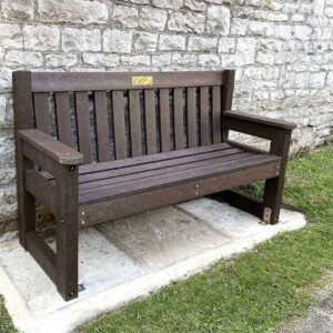 The stone wall sets off the traditional Dale bench in Brown at Tideswell in Derbyshire witha brass plaque