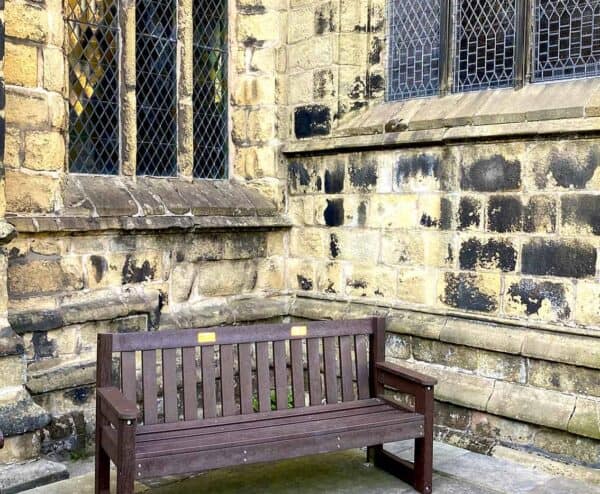 Traditional Dale bench in Brown at Tideswell church in Derbyshire with brass plaques