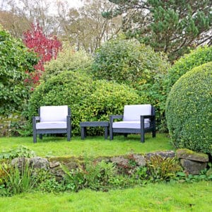 Derbyshire Chairs with arms and table in Black from the front in a garden setting